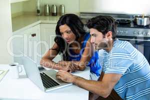 Young couple using laptop in kitchen