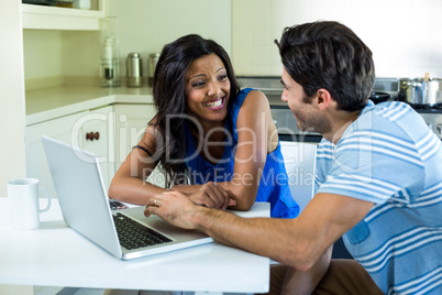 Young couple using laptop in kitchen