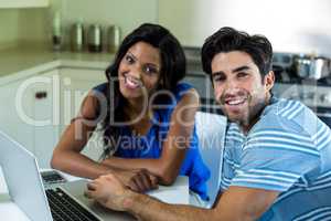 Portrait of young couple using laptop in kitchen