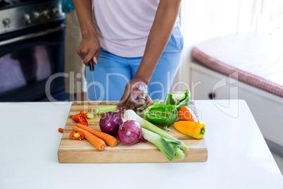 Mid-section of woman chopping vegetable in kitchen
