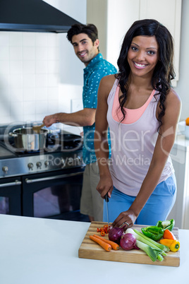 Portrait of young couple cooking food together in kitchen