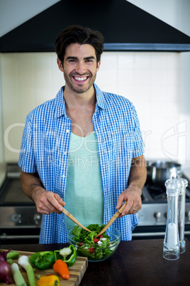 Portrait of man mixing a salad in kitchen