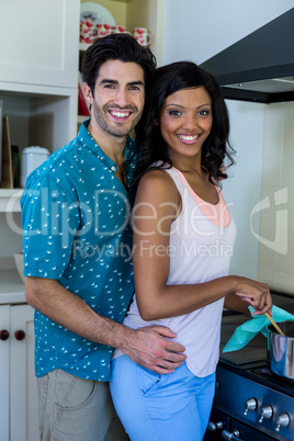 Man embracing woman while cooking in kitchen