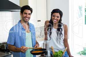 Portrait of young couple cooking food together in kitchen