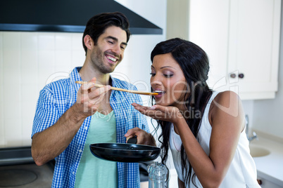 Man feeding woman while cooking in kitchen
