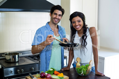 Portrait of young couple cooking food together in kitchen