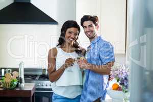 Young couple toasting glasses of wine in kitchen