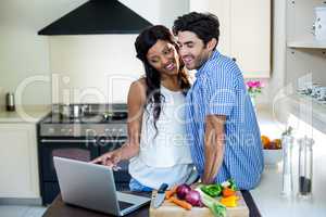 Young couple using laptop in kitchen