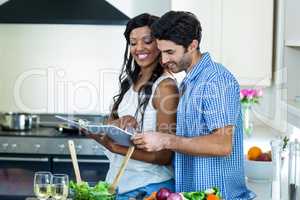 Young couple looking at recipe book in kitchen