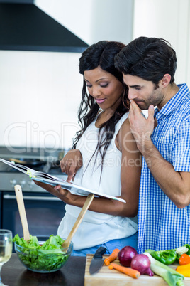 Young couple looking at recipe book in kitchen