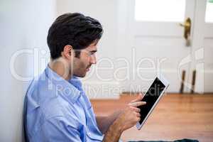 Man sitting on floor and using digital tablet