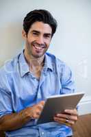 Portrait of man sitting on floor and using digital tablet