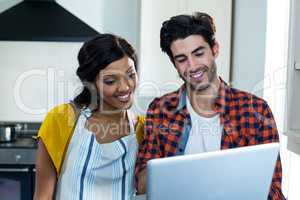 Young couple using laptop in kitchen