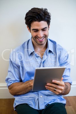 Man sitting on floor and using digital tablet
