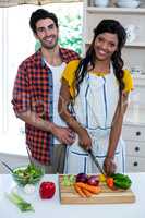 Portrait of couple chopping vegetables in kitchen