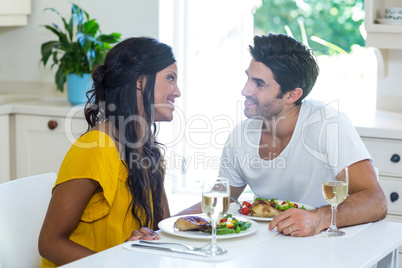 Young couple talking while having meal in kitchen