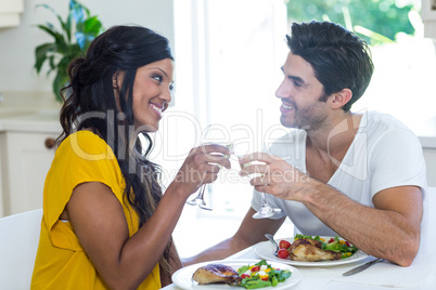 Couple toasting wine glasses while having meal in kitchen