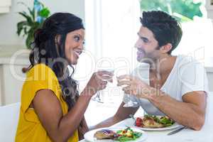 Couple toasting wine glasses while having meal in kitchen