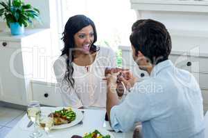 Man gifting finger to woman while having lunch