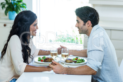 Young couple talking while having meal in kitchen Young couple talking while having meal in kitchen