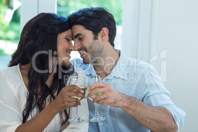 Young couple rubbing their nose while toasting wine