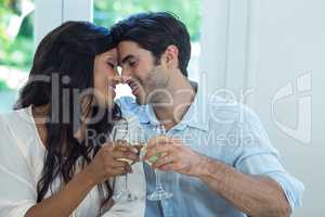 Young couple rubbing their nose while toasting wine