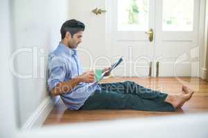 Man reading newspaper while having coffee