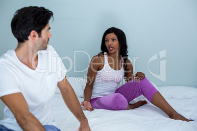 Young couple arguing on bed in bedroom