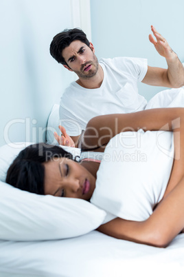 Young couple arguing on bed in bedroom