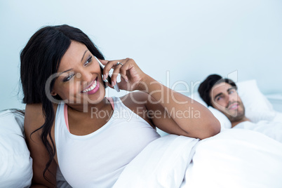 Woman lying on bed and talking on phone