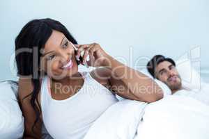 Woman lying on bed and talking on phone
