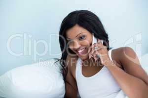 Woman lying on bed and talking on phone