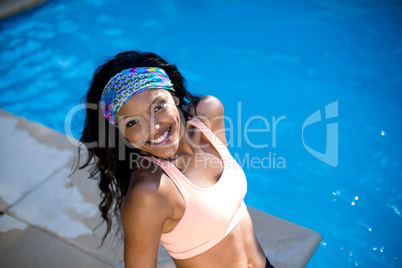 Beautiful young woman sitting by the poolside