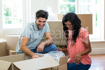 Young couple unpacking carton boxes in their new house