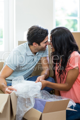 Young couple unpacking carton boxes in their new house