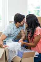 Young couple unpacking carton boxes in their new house