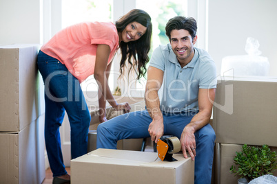 Young couple unpacking carton boxes in their new house