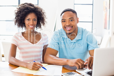 Young couple using laptop while checking bills