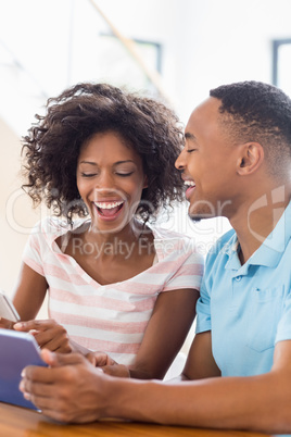 Happy couple using mobile phone and digital tablet