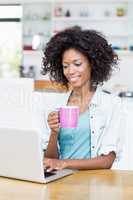 Woman using laptop while having coffee