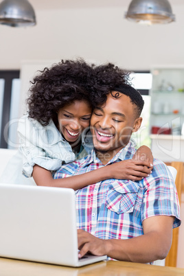 Happy young couple using laptop in kitchen