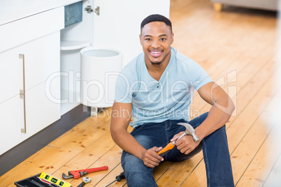 Man showing a hammer while working with a set of tools