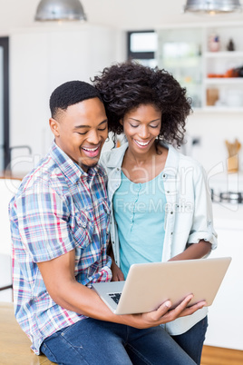Happy young couple using laptop in kitchen Happy young couple using laptop in kitchen