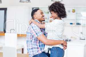 Young couple embracing face to face in kitchen