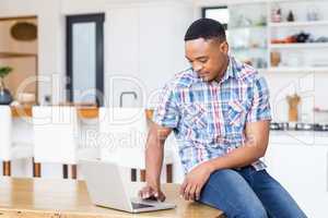 Young man using laptop in kitchen