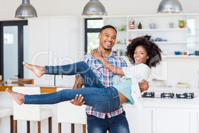 Man lifting woman in his arms in kitchen