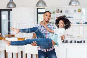 Man lifting woman in his arms in kitchen