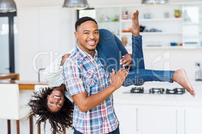 Man lifting his woman in kitchen