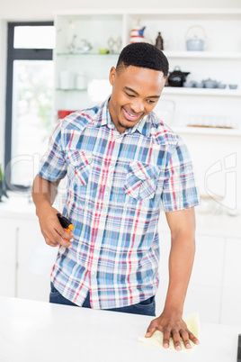 Smiling man cleaning kitchen counter