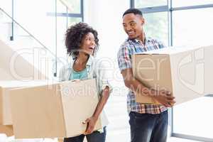 Smiling young couple holding a carton in their new house